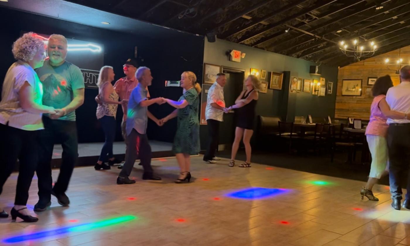 Dancers at the St. Augustine Rug Cutters event on a smooth wooden dance floor
