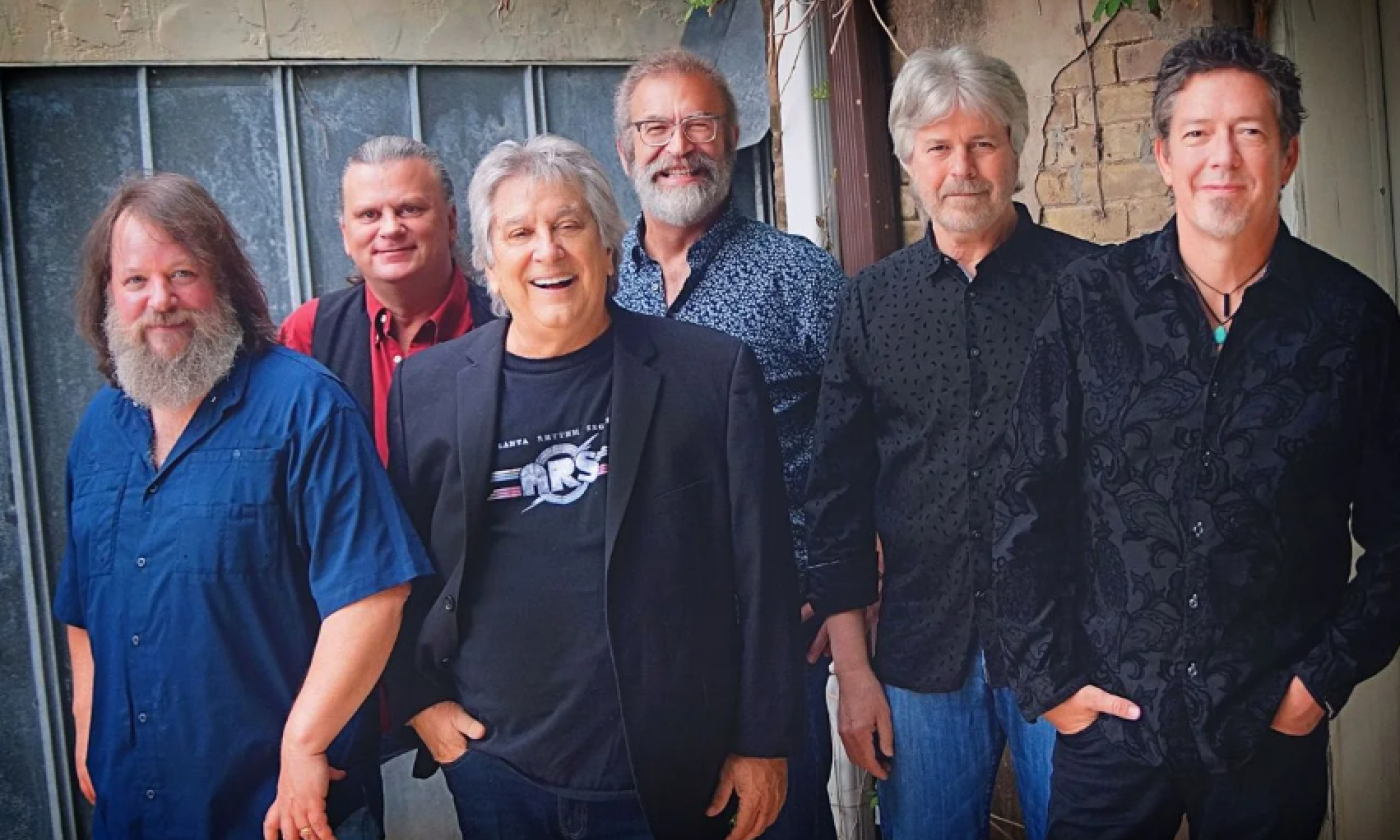 Bandmates from Atlanta Rhythm Section pose in front of a rustic house.