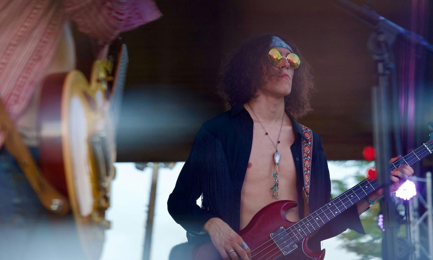 A hippy performs music on stage.