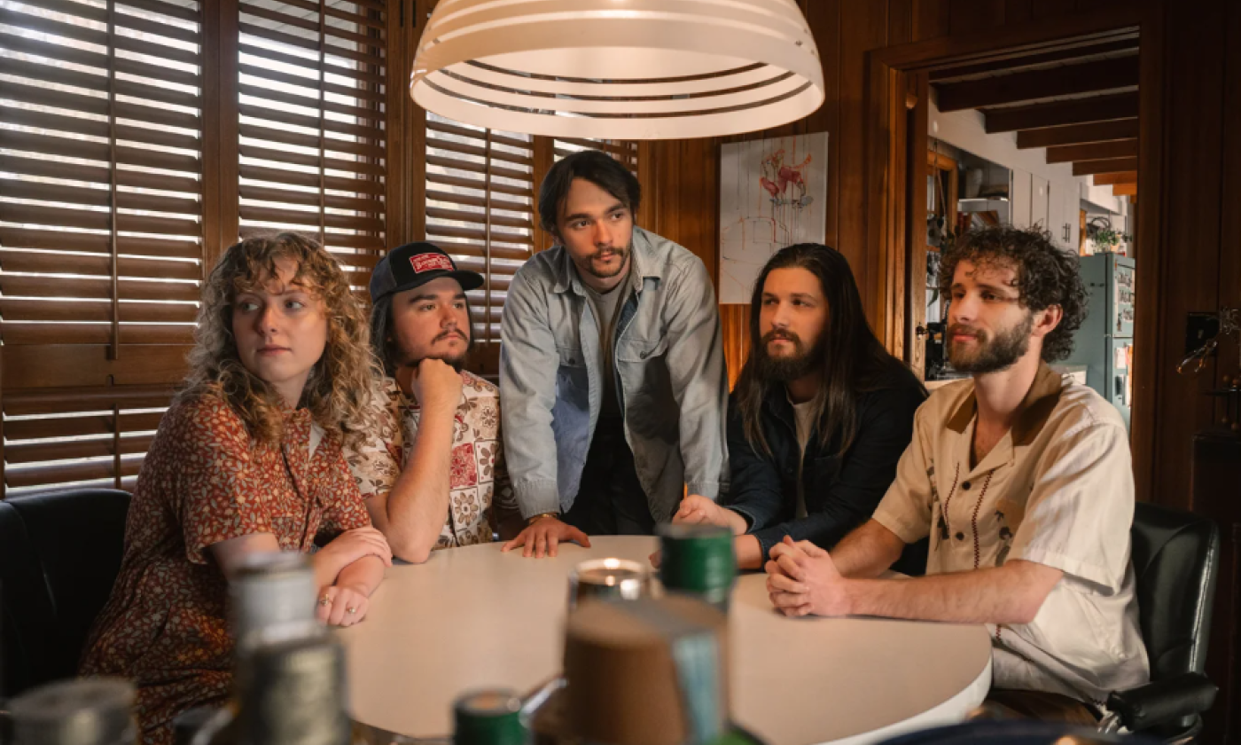 Members of Shadowgrass gather around a table beneath a hanging lamp.