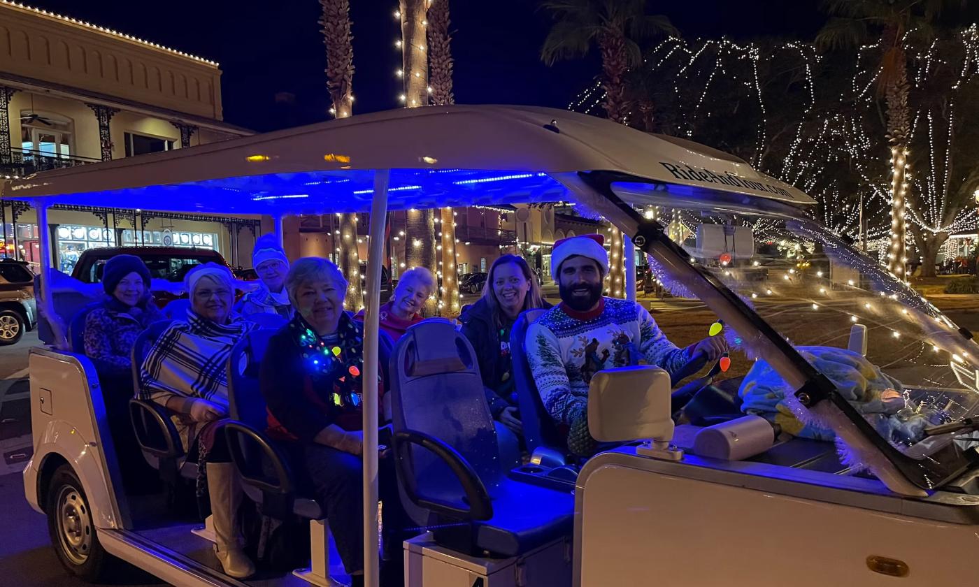 People riding a golf cart watching the holiday lights