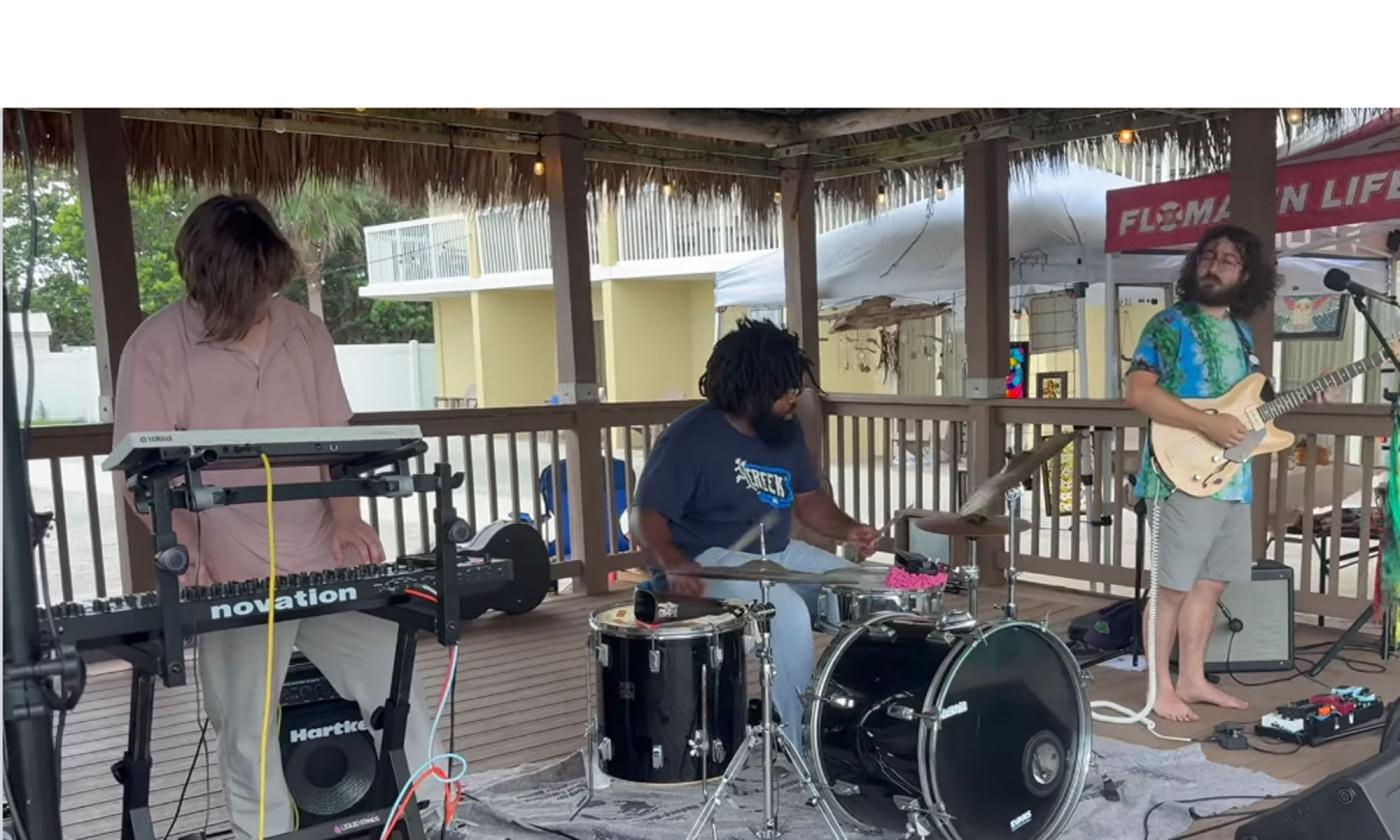 The band Vinegar playing onstage; keyboards, drums, guitar, and vocals.