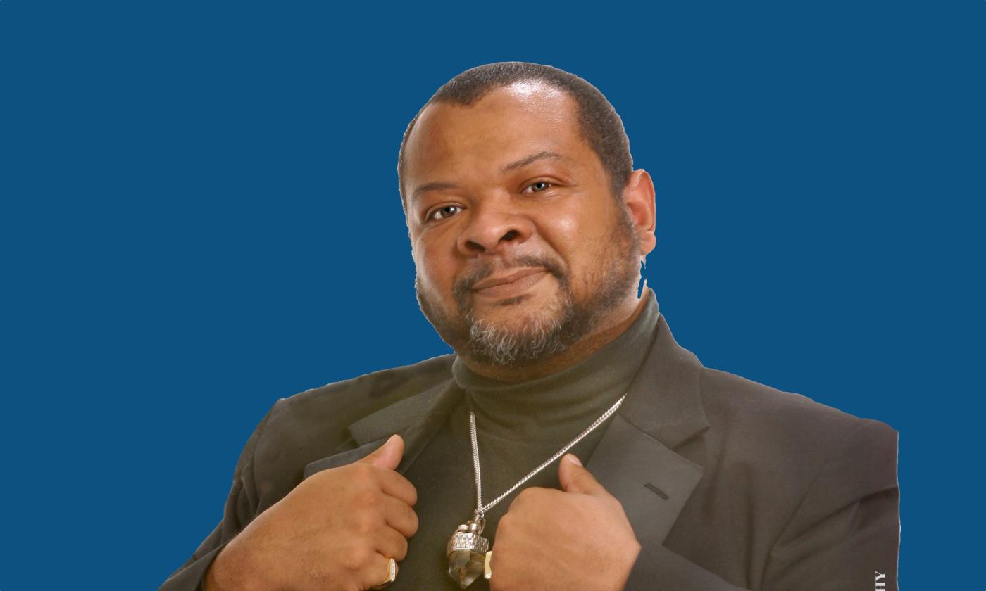 Concert Pianist Kevin Sharp in a black suit against a blue background