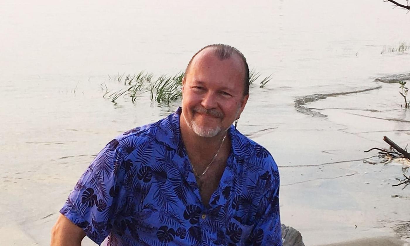 Dave Gruuve Sisk sitting by the waterway, smiling