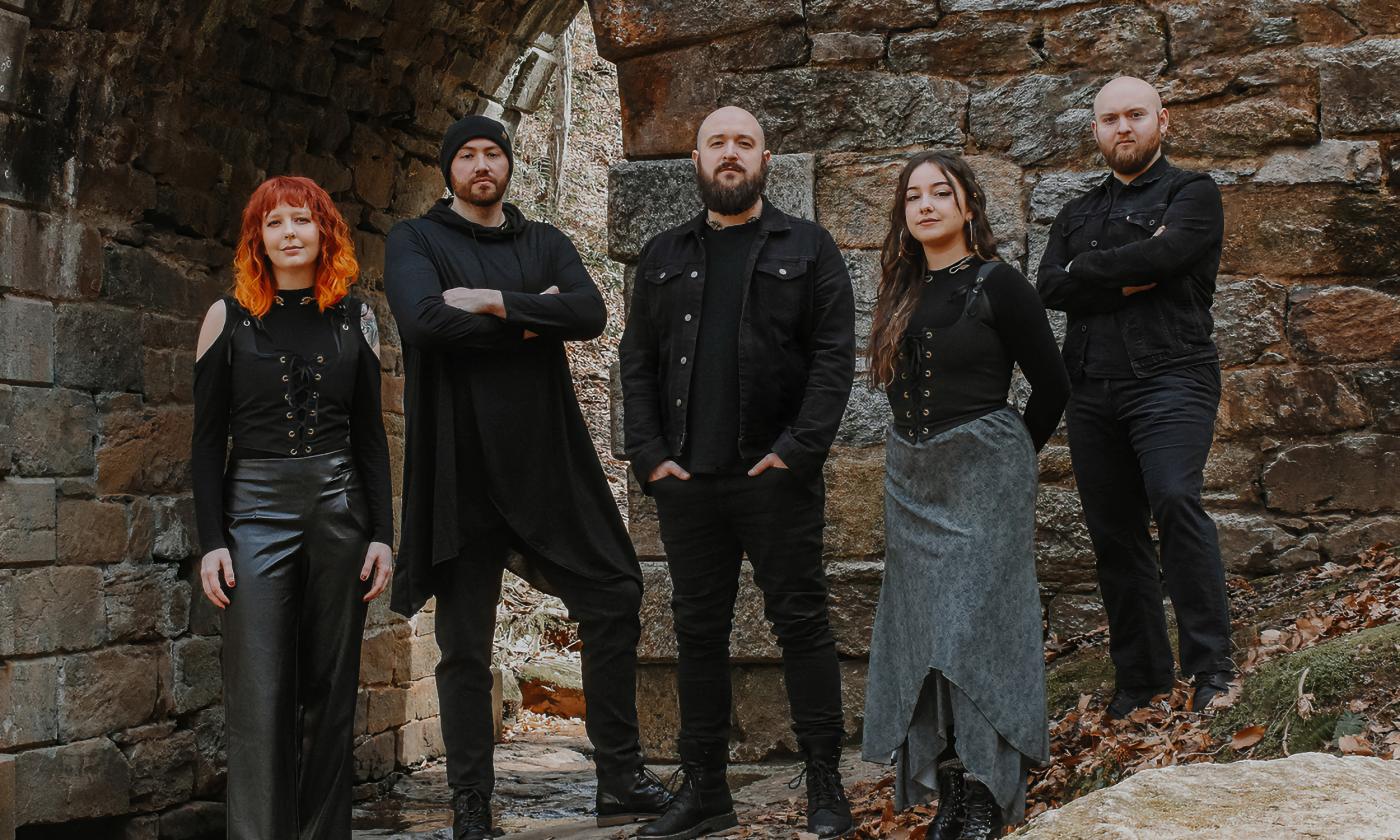 Members of SYR, a 5-person Celtic band, wearing black in front of an old fort or castle