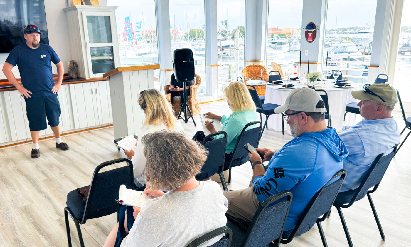 People inside attending a boating seminar with a view of the marina