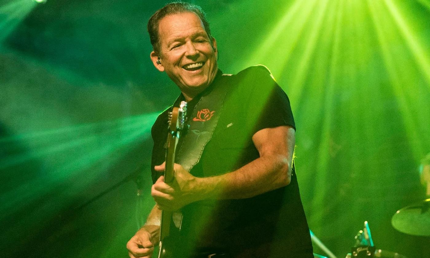 Tommy Castro wears black clothing and performs live on stage.