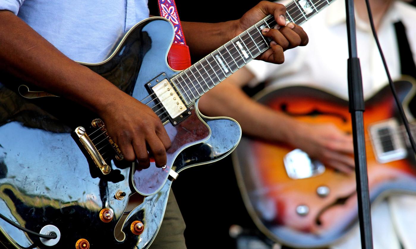 Two men playing guitars on stage, focused on the guitars and their hands
