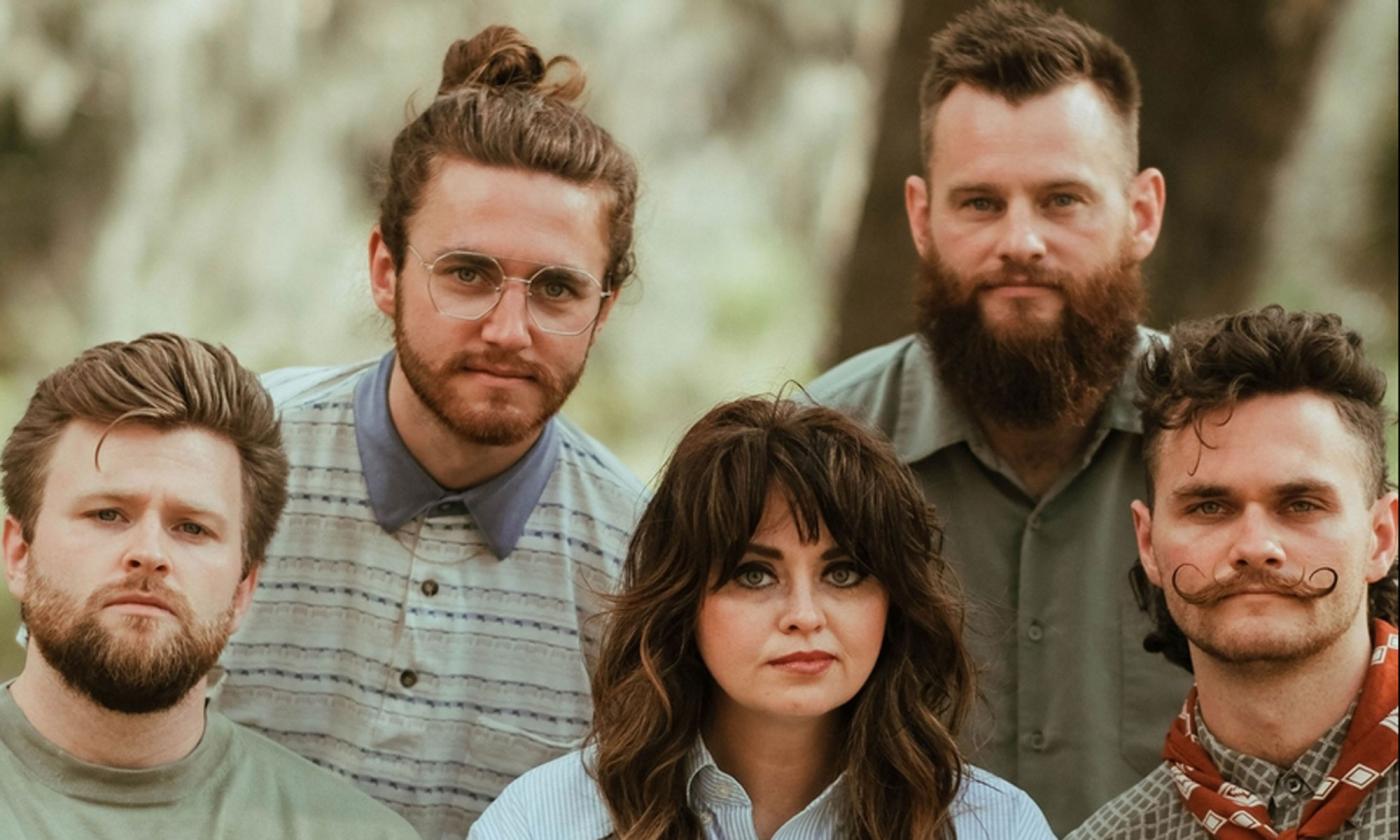 the band Dawson Hollow sitting together, with trees in the background