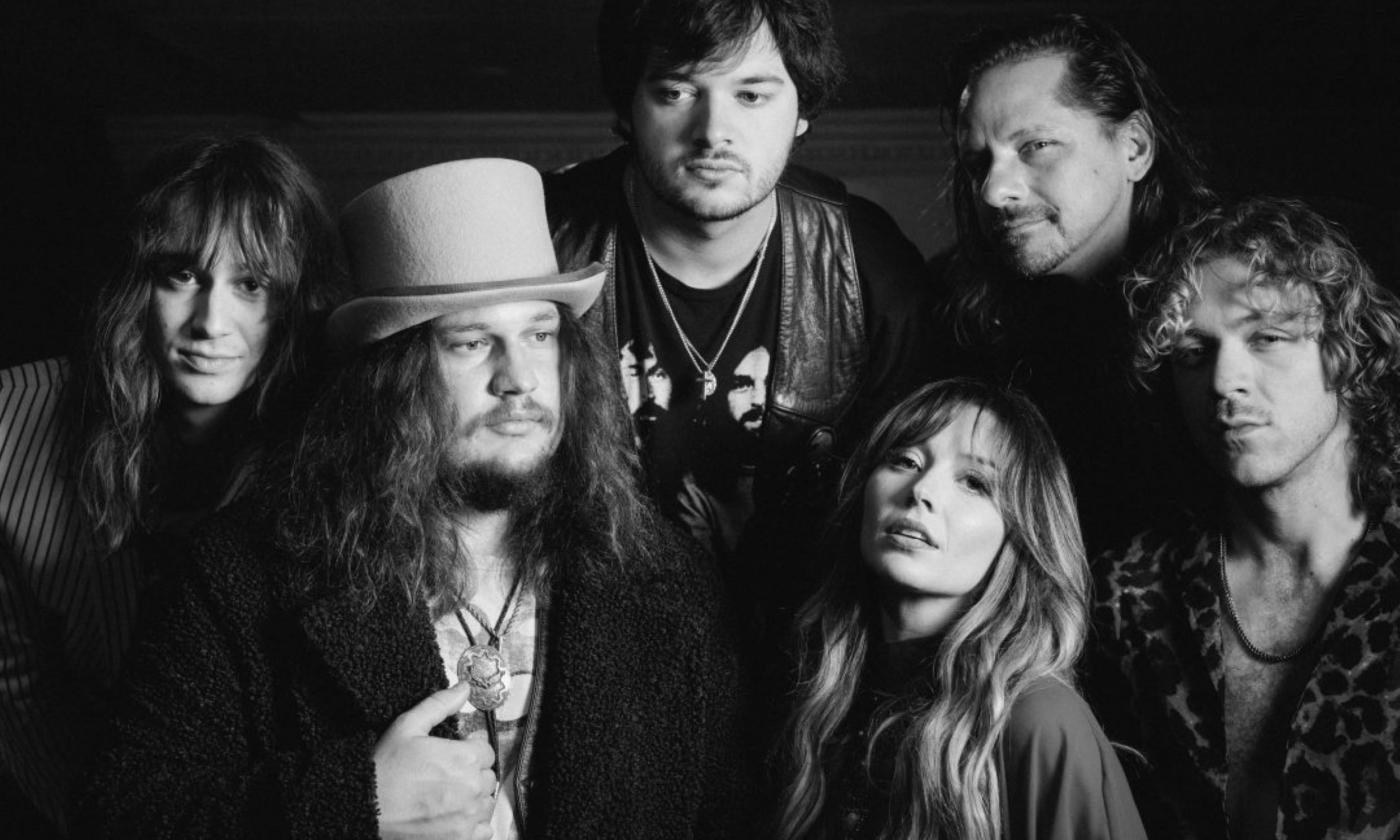 Bandmates from Parker Barrow huddle together and pose in front of a black backdrop.