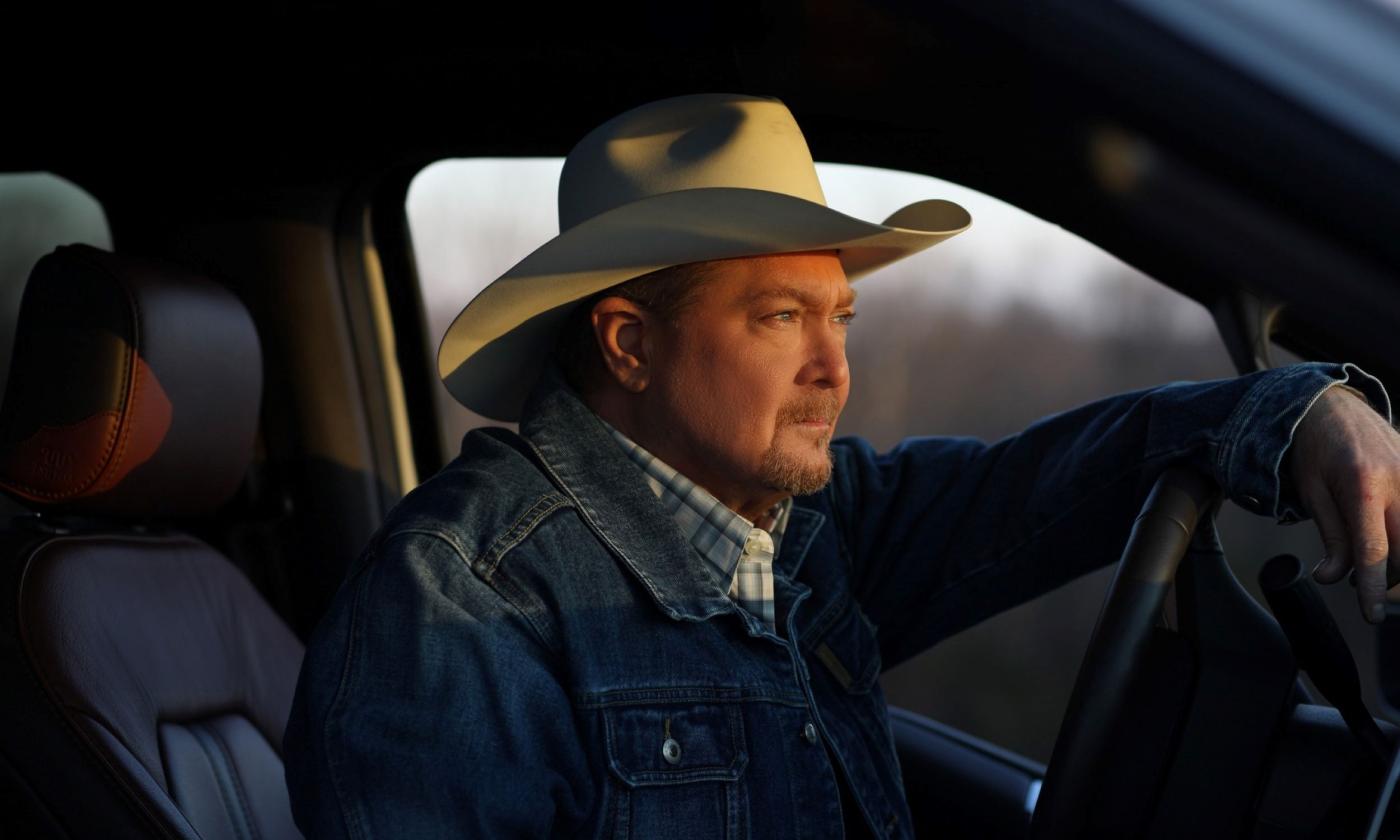 Tracy Lawrence wears a denim jacket and poses in a truck. 
