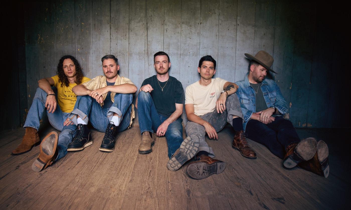 Members of the five-piece band Lanco, seated on a wooden floor