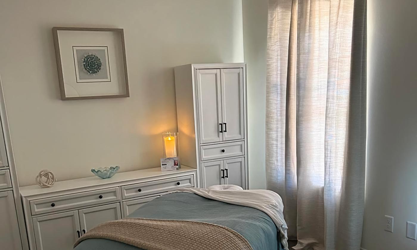 A tranquil spa treatment room in cream and soft blue with a lit candle