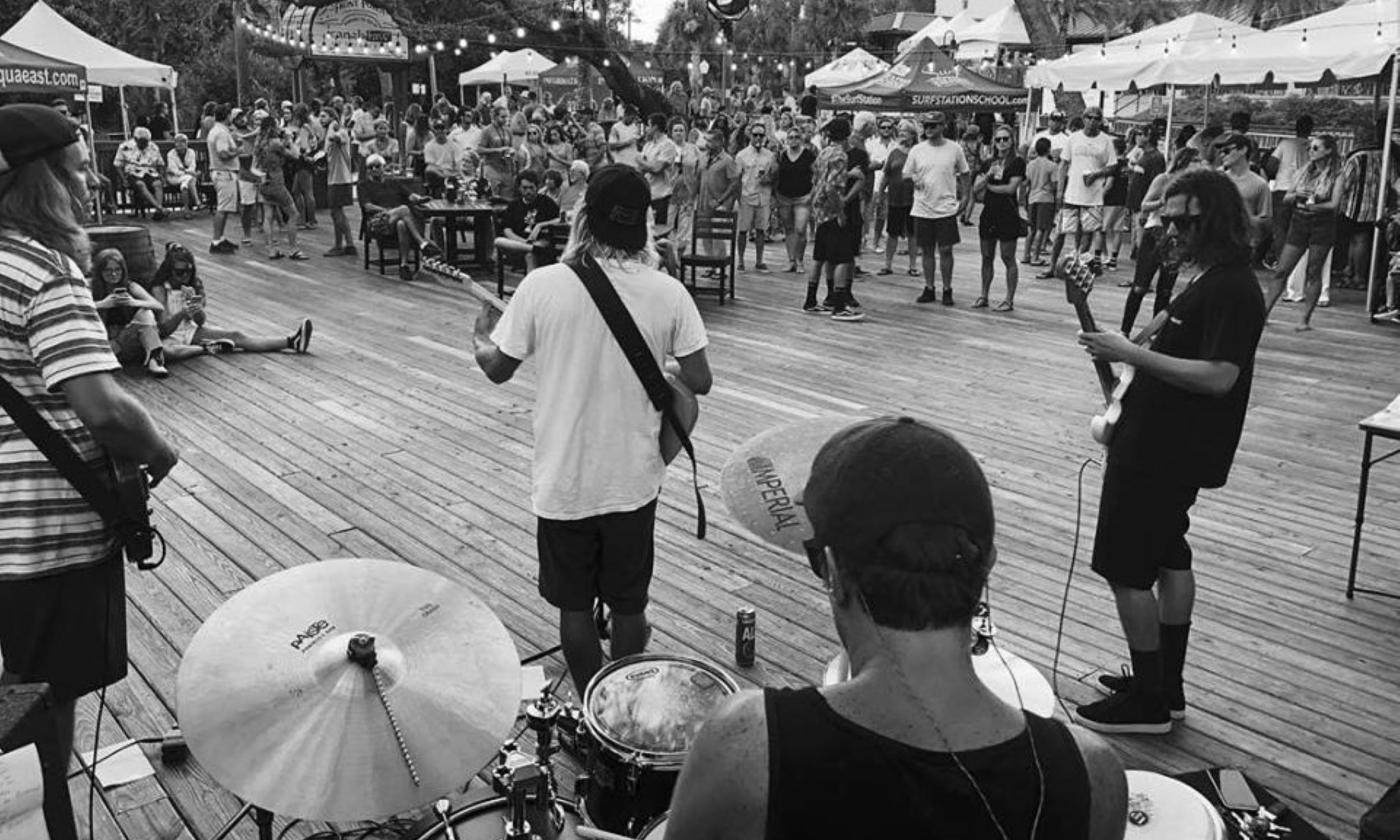 Kelp performs on stage with their guitars and drums.