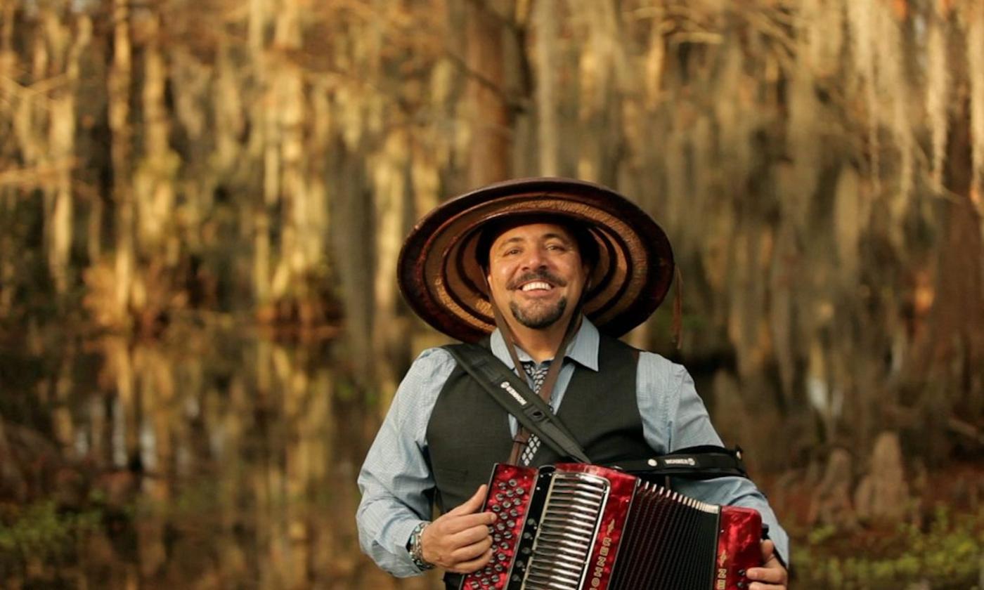 Terrance Simien beams as he stands before a scenic bayou backdrop.