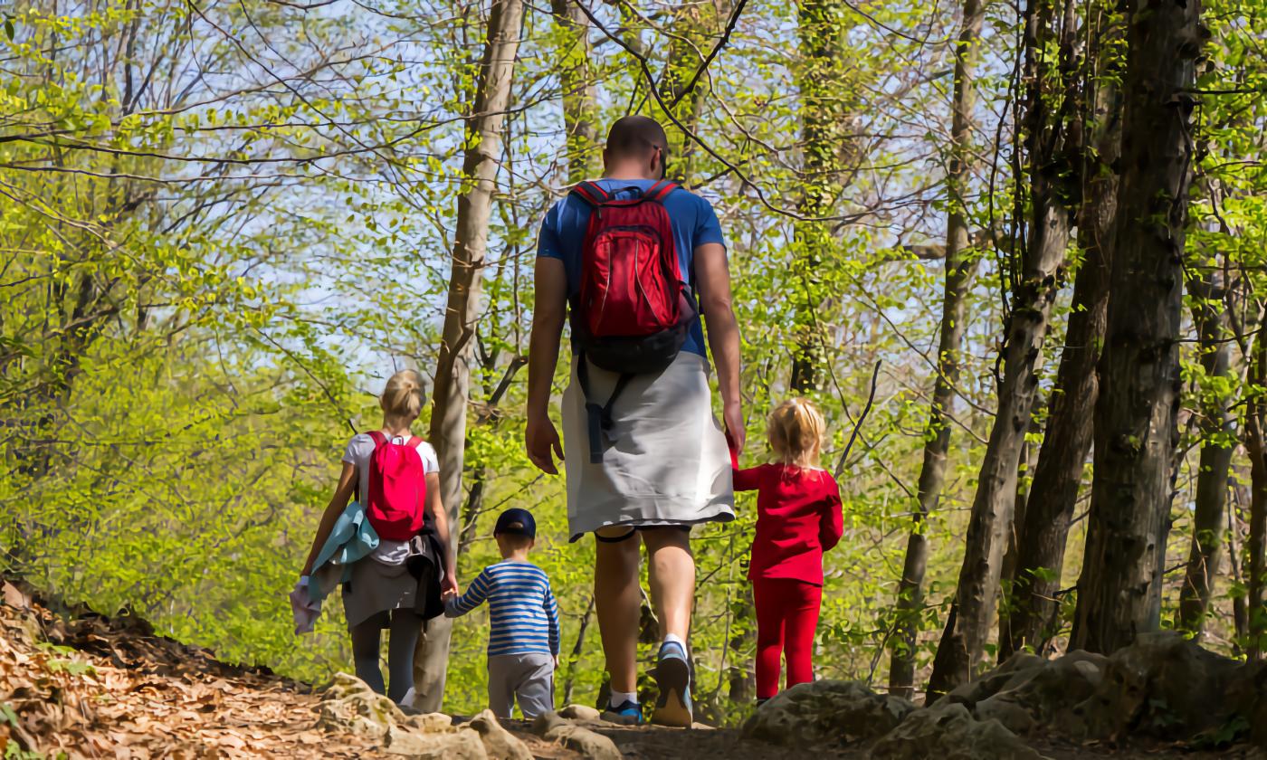 A dad and three young children on a nature walk