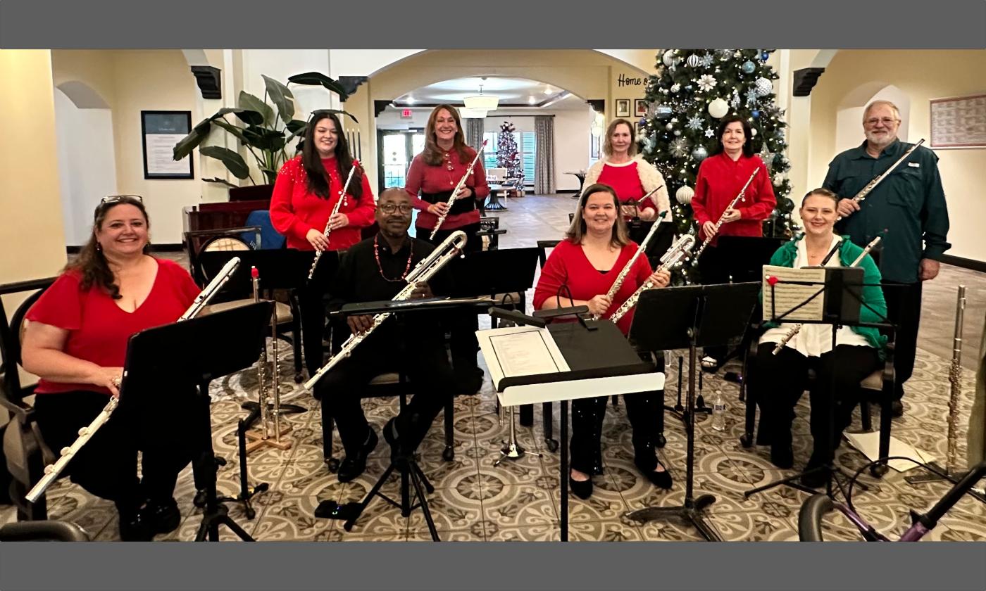 A fute choir, wearing red tops, standing near a Christmas tree