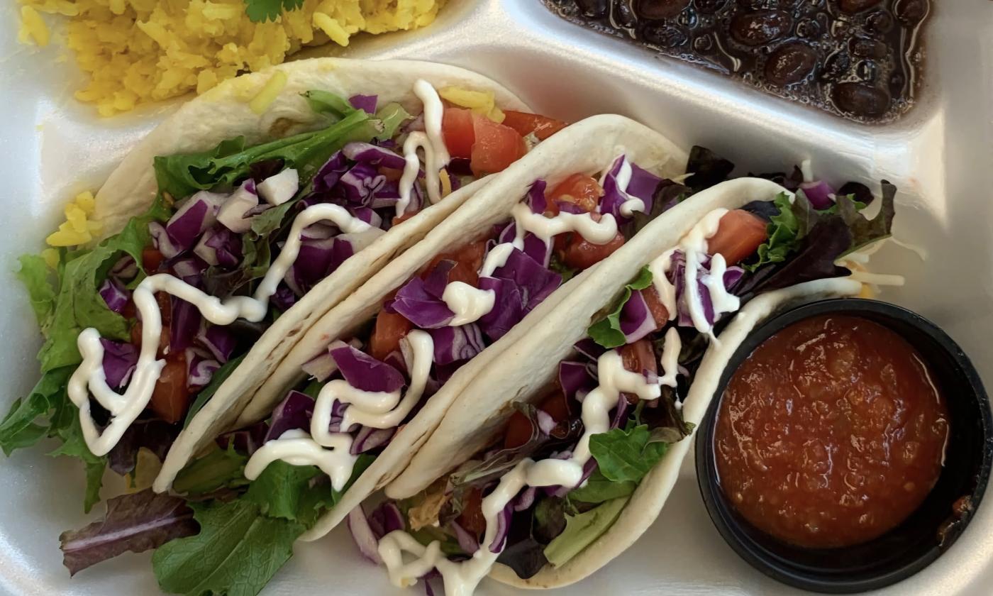Tacos with a side of salsa in a to-go box