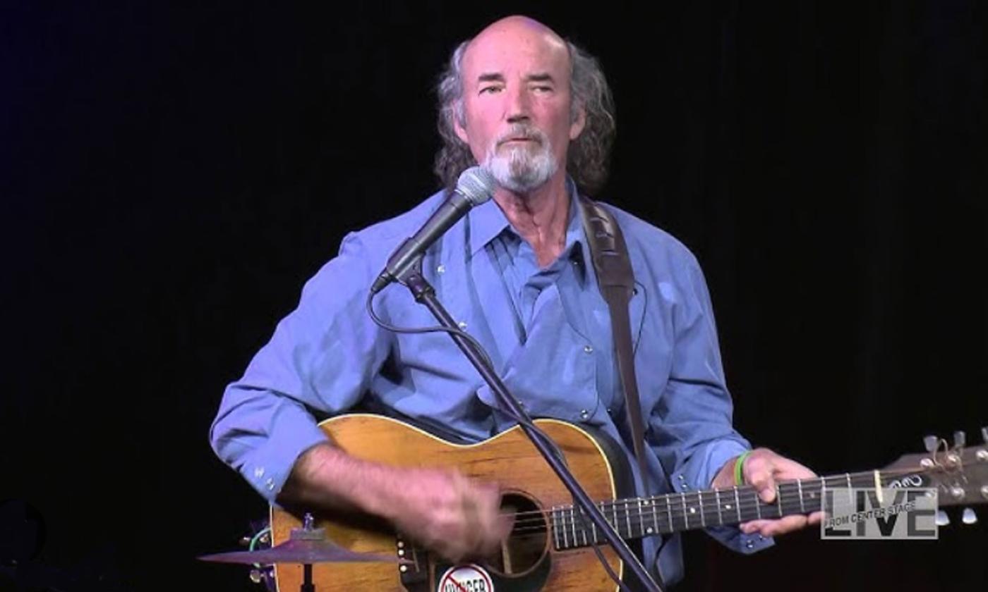 Musician Chakulla onstage with guitar, in front of mike