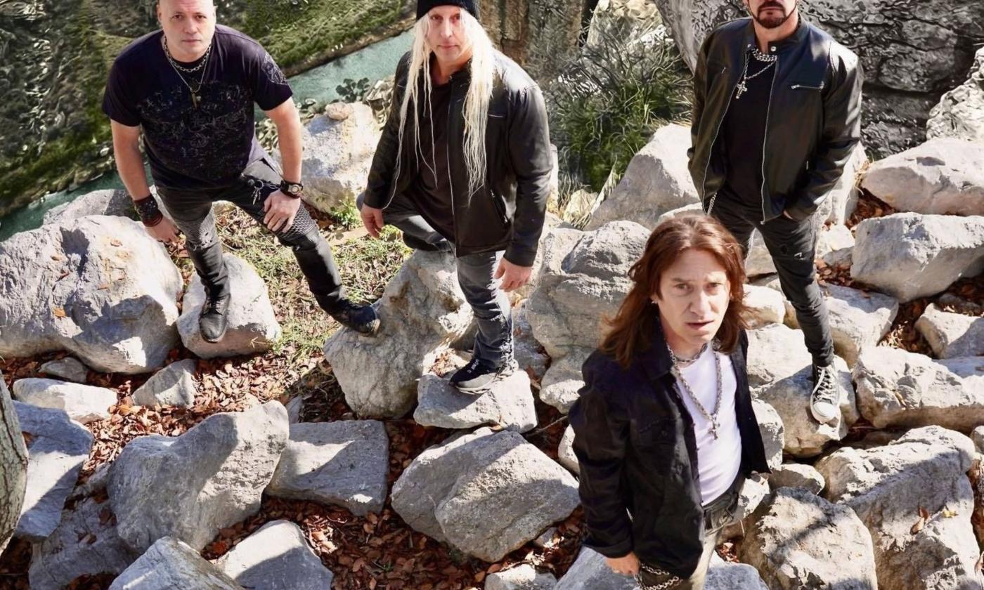 Members of Human Clay, dressed in black, stand atop rugged rock formations for a dramatic band portrait.