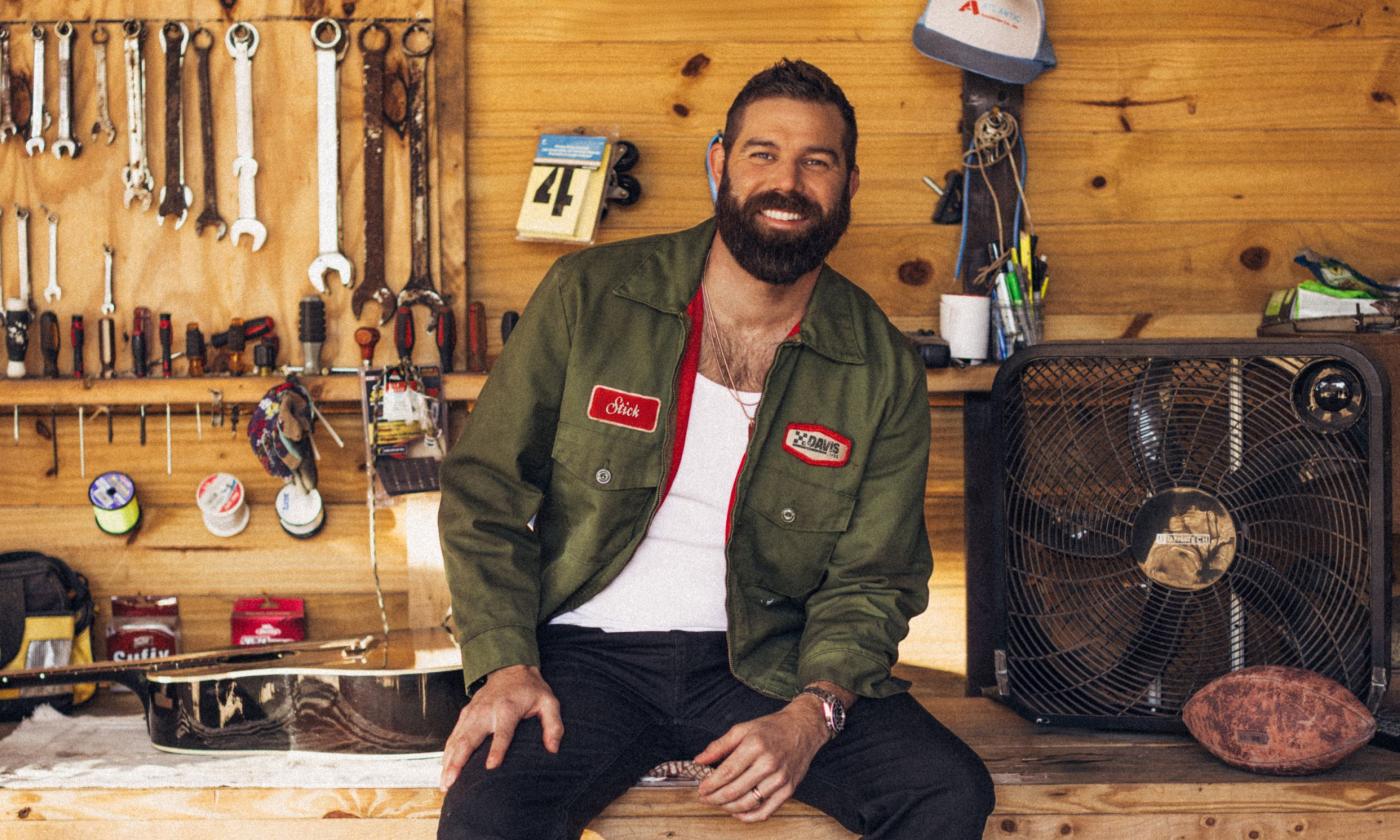 Jordan Davis smiles and poses in front of a tool shed. 