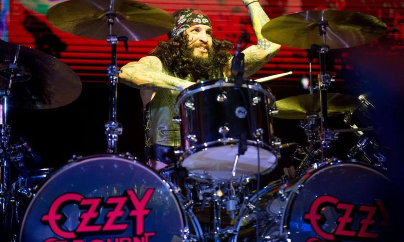 A bandmate from Tommy's Rocktrip smiles and performs on stage.
