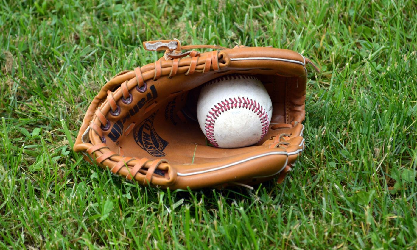 A baseball in a glove on the grass