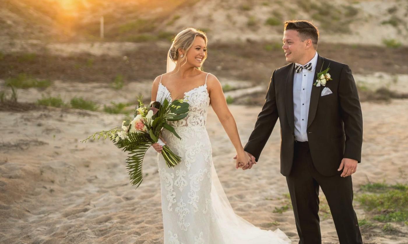 A bride and groom walking on the beach