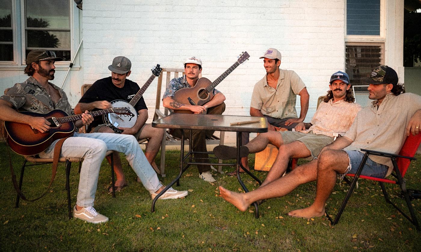 Members of Twin Fin, sitting in chairs on a lawn