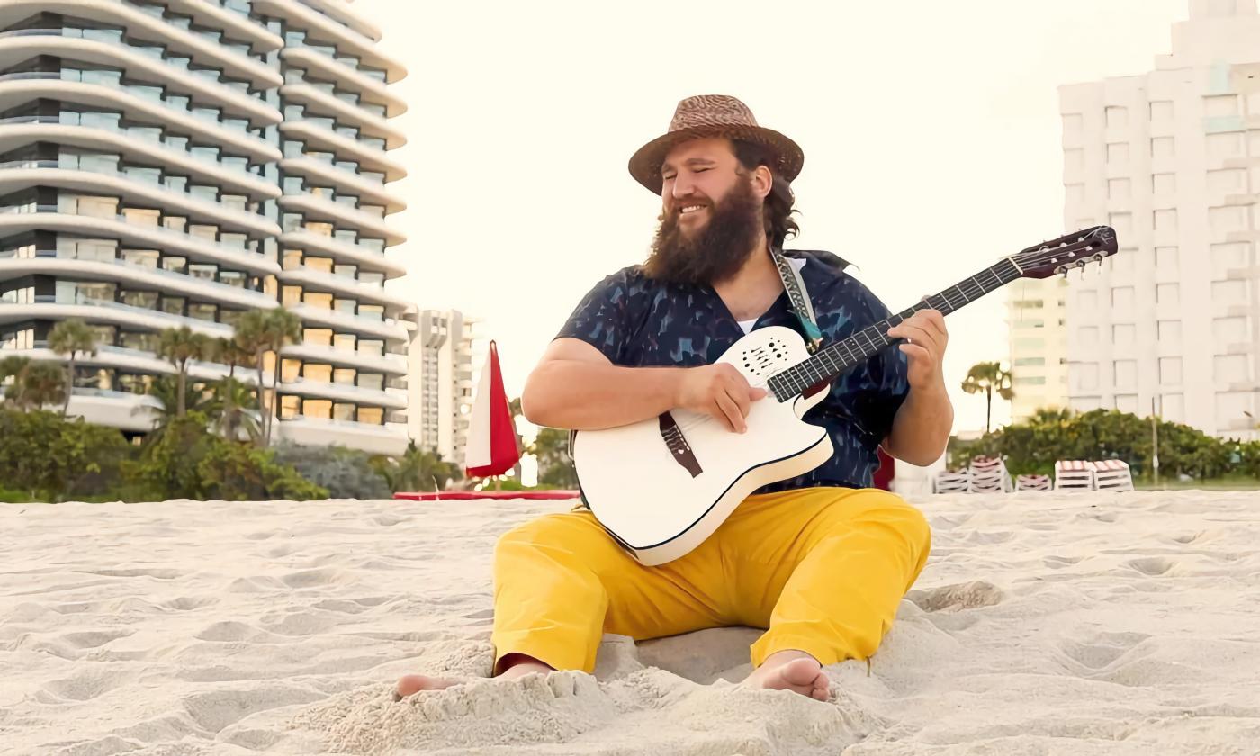 Zach Deputy sitting in the sand on a Miami Beach