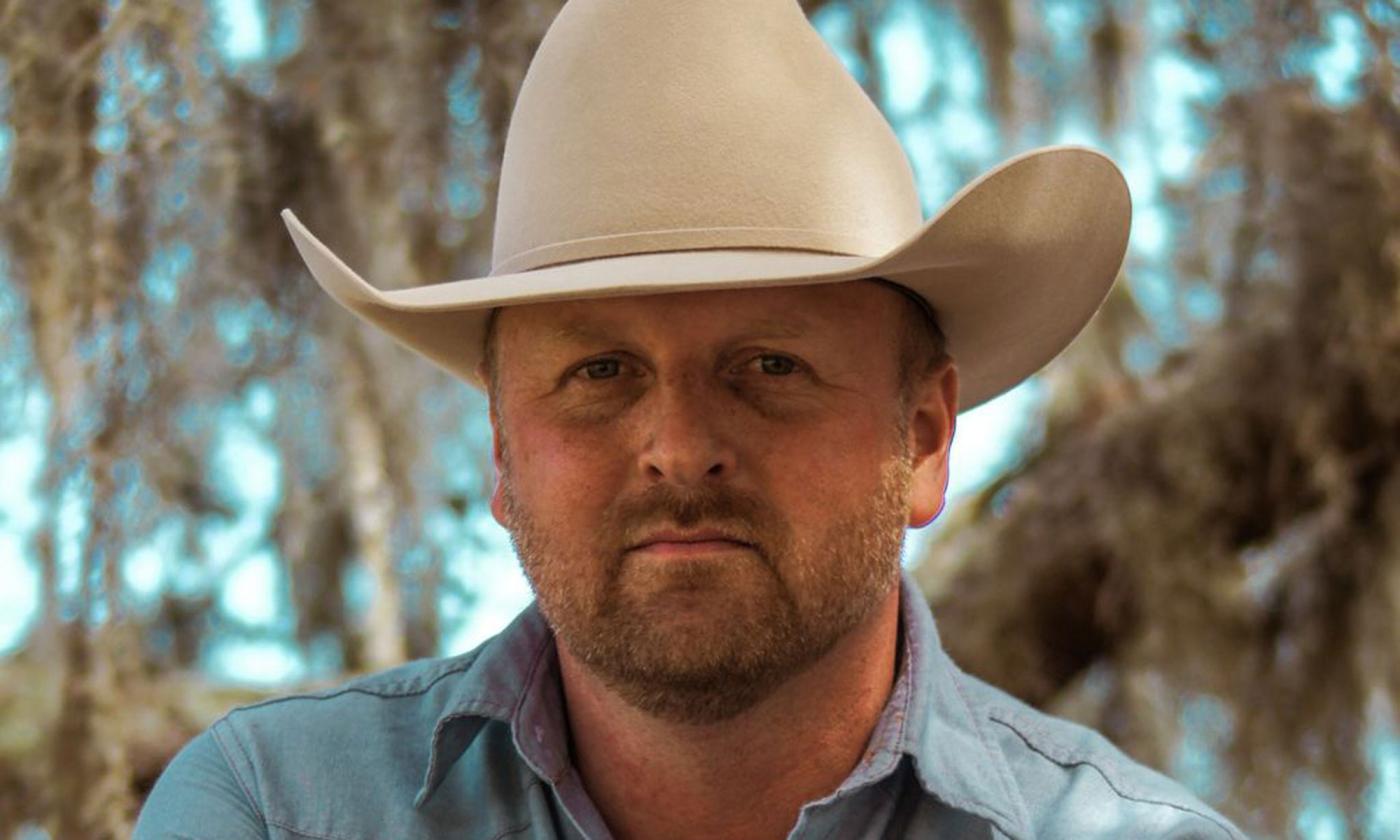songwriter Eli Mosely standing outside, in white cowboy hat
