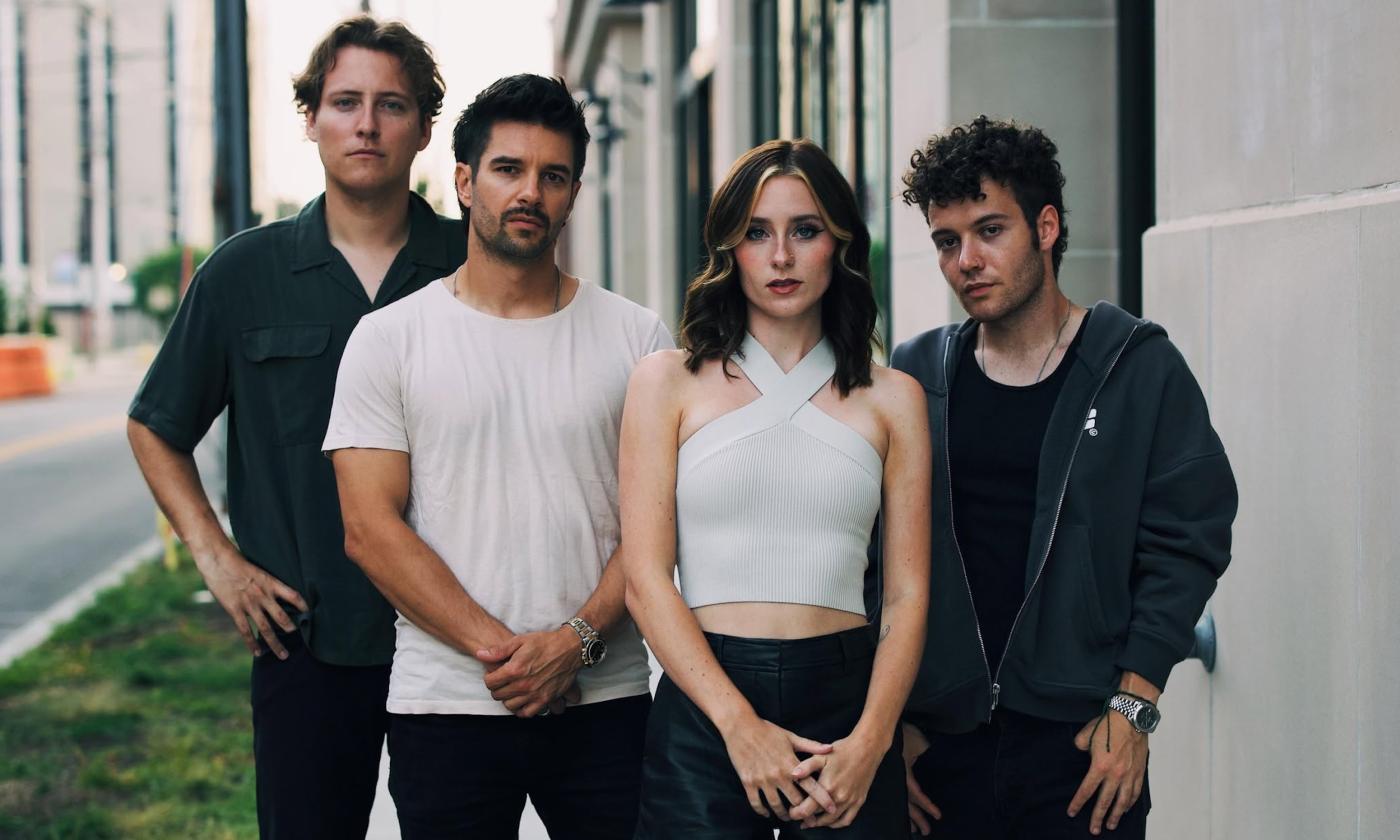 Members of First To Eleven, dressed in black and white, strike a pose on a city street.