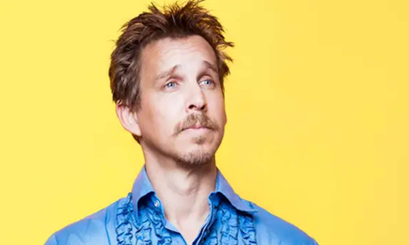 Jason Salmon wears a blue shirt and poses in front of a yellow backdrop.