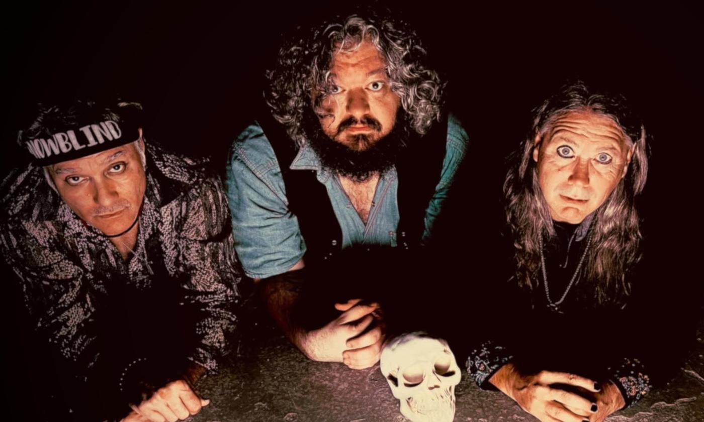 Bandmates from Snowblind pose in front of a human skull.