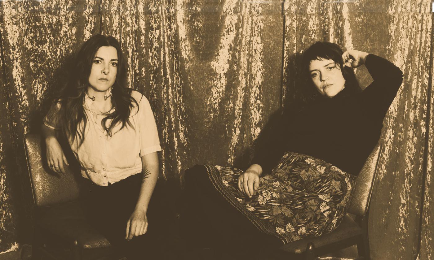 The duo Mama's Broke depicted in front of a shiny curtain in a tintype style