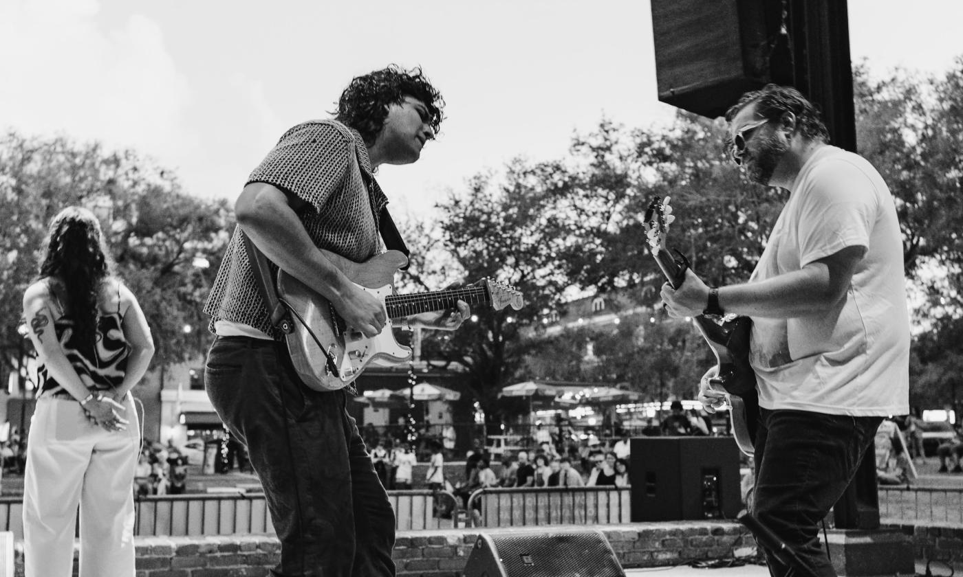 Thomas Allain and his band on stage, with Thomas and the lead guitarist playing together
