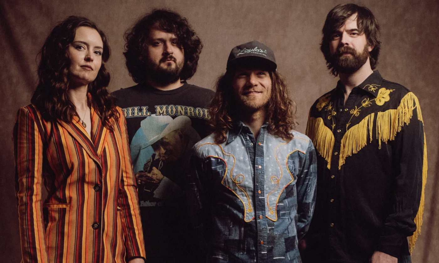Bandmates from East Nash Grass pose in front of a suede brown backdrop.