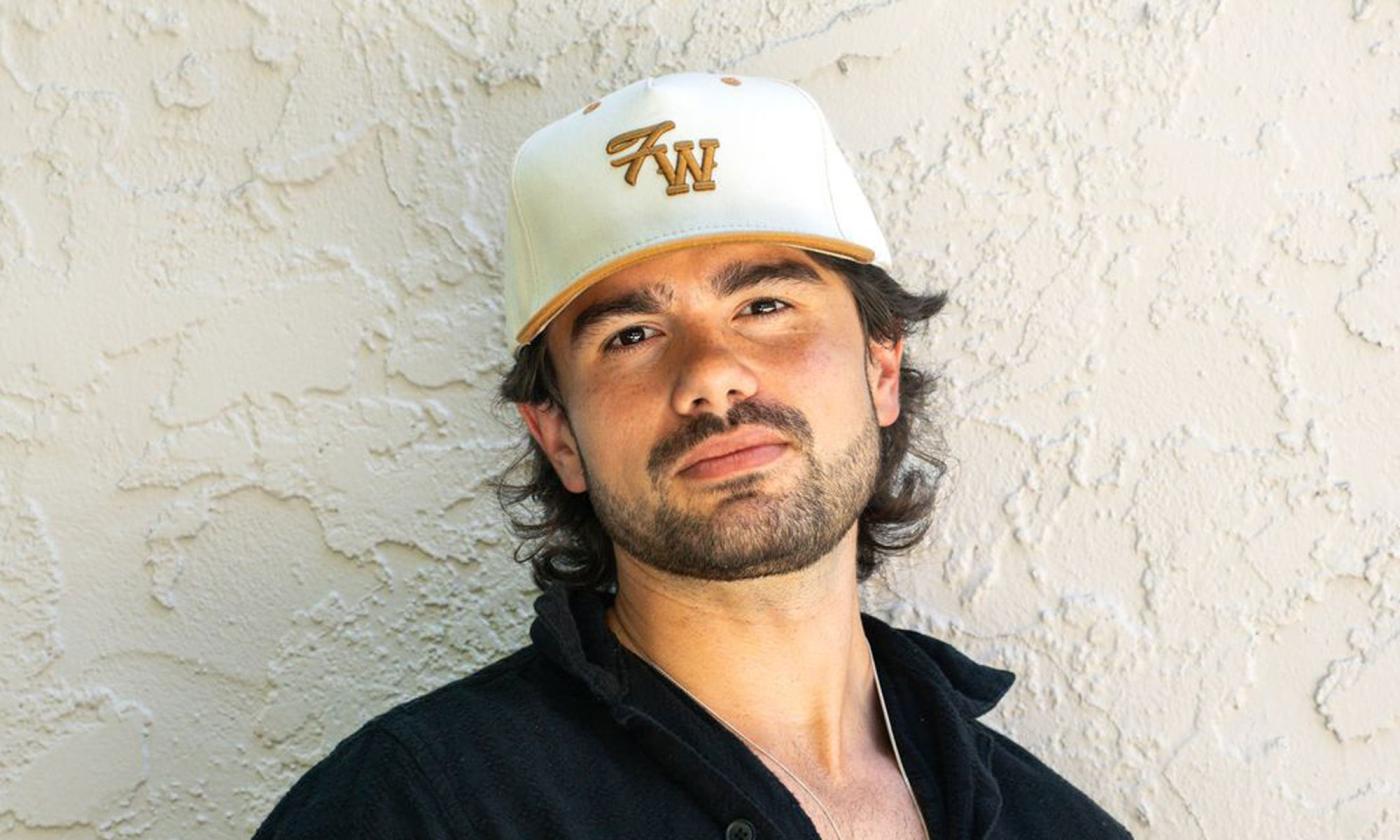 Composer Emmett Stevens, Jr standing in front of white wall, in a ball cap