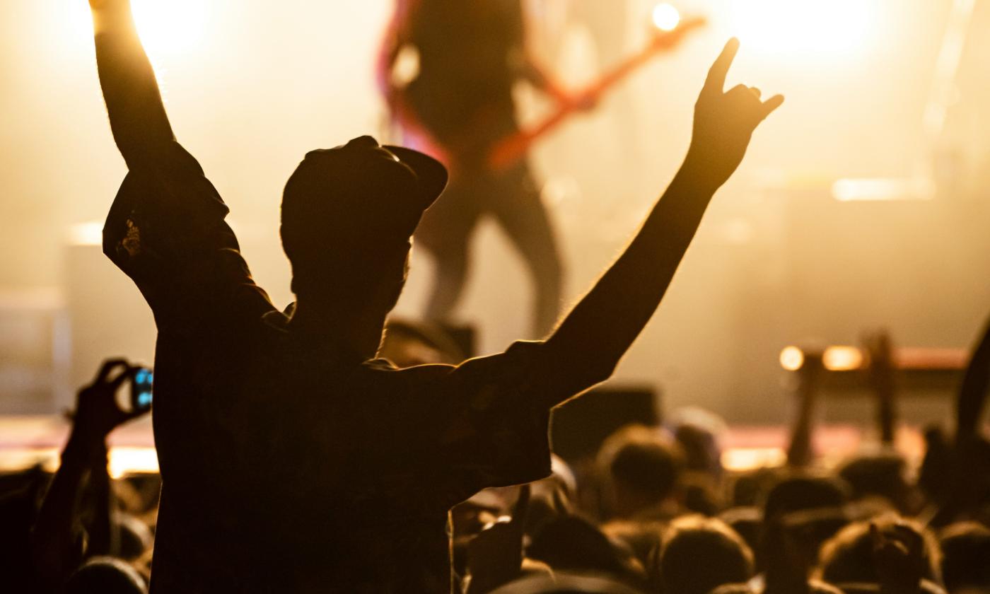 A fan raises his hands and listens to a live performance.