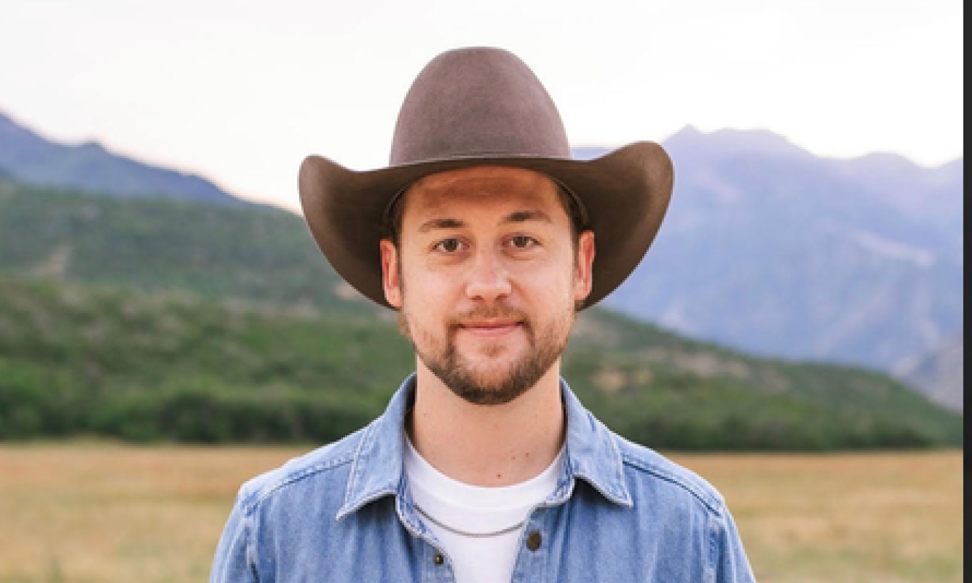 Songwriter Sam Banks in cowboy hat, standing outside