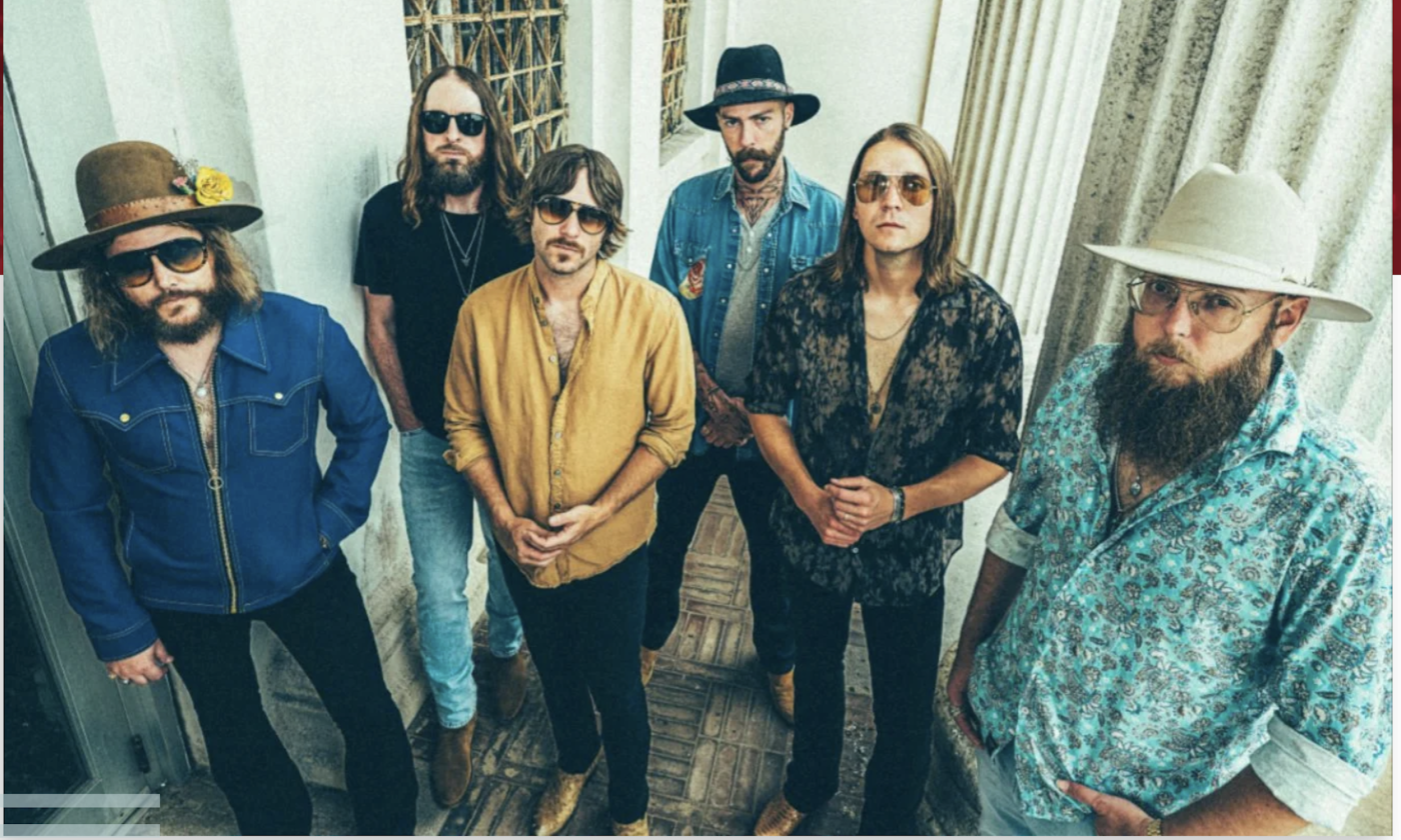 Bandmates from Whiskey Myers pose while using a white building with pillars as their backdrop. 