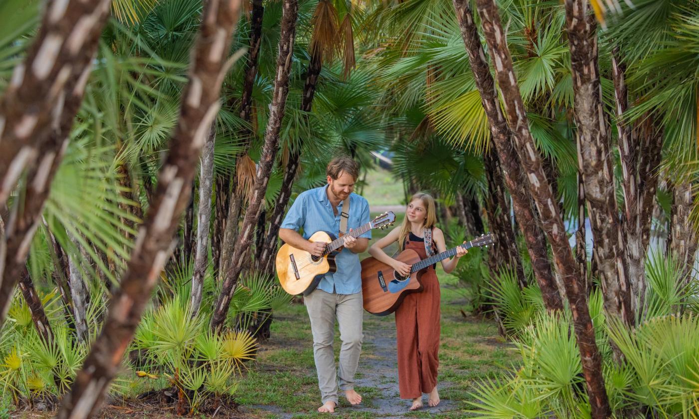 Bystrom & Bear playing guitar in the woods