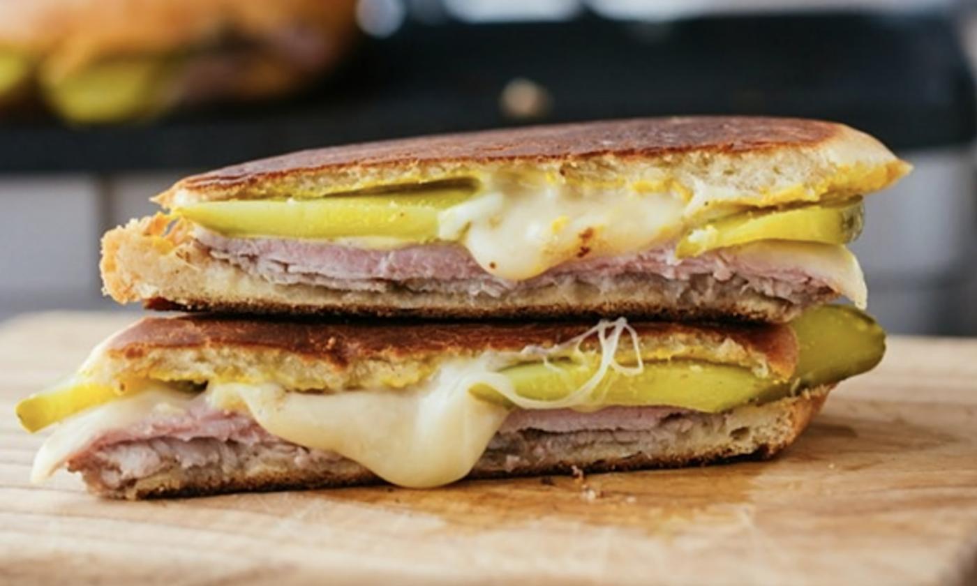 Two halves of a Cuban Sandwich, oozing with cheese