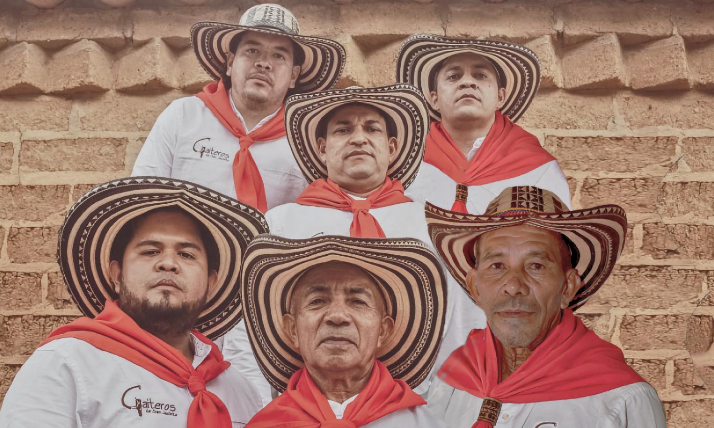 The five musicians of Los Gaiteros de San Jacinto, wearing white shirts, red bandanas, and traditional hats