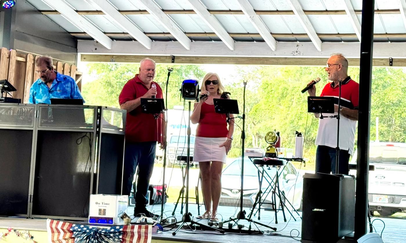 Four members of a vocal group standing on a covered out-door stage