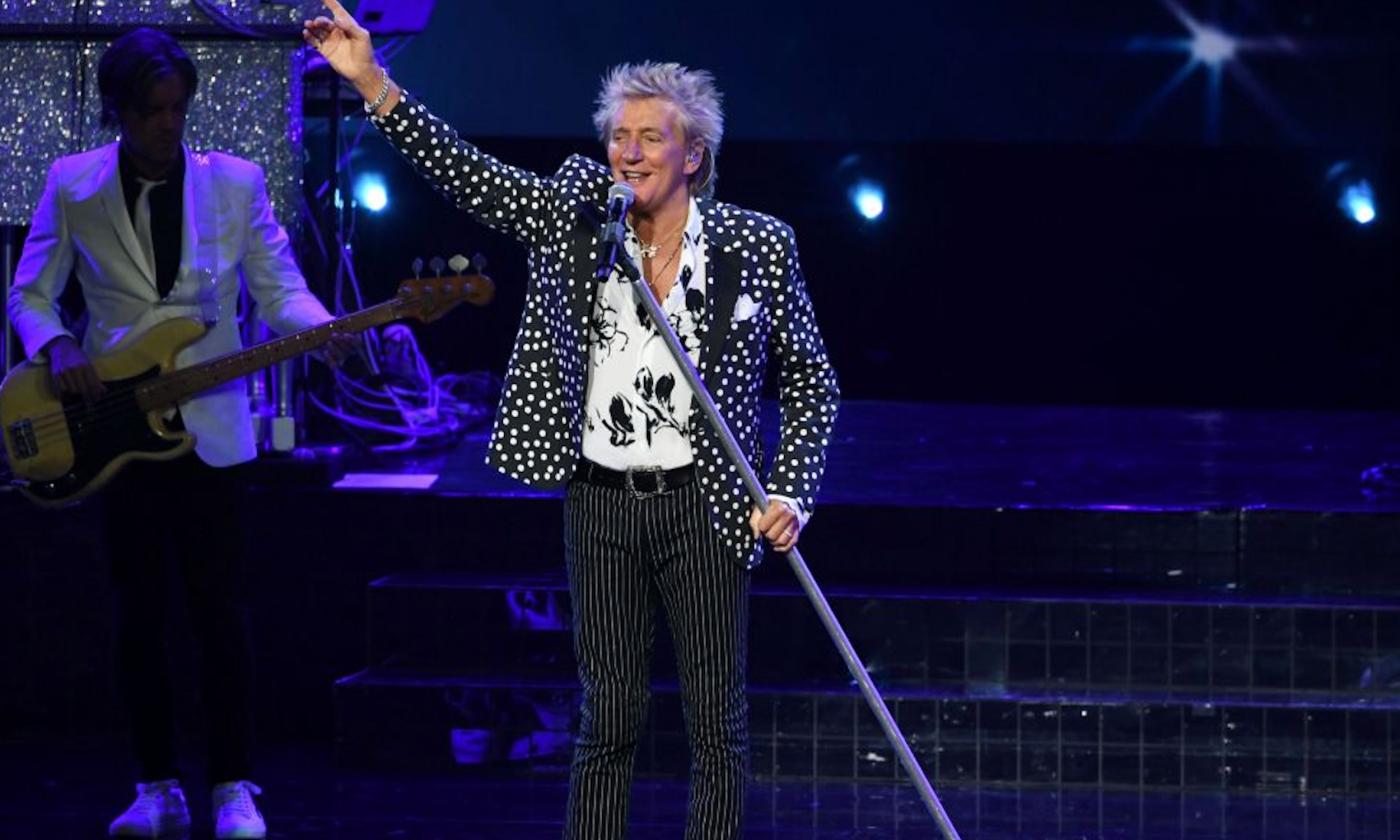 Rod Stewart performs on stage for fans. 