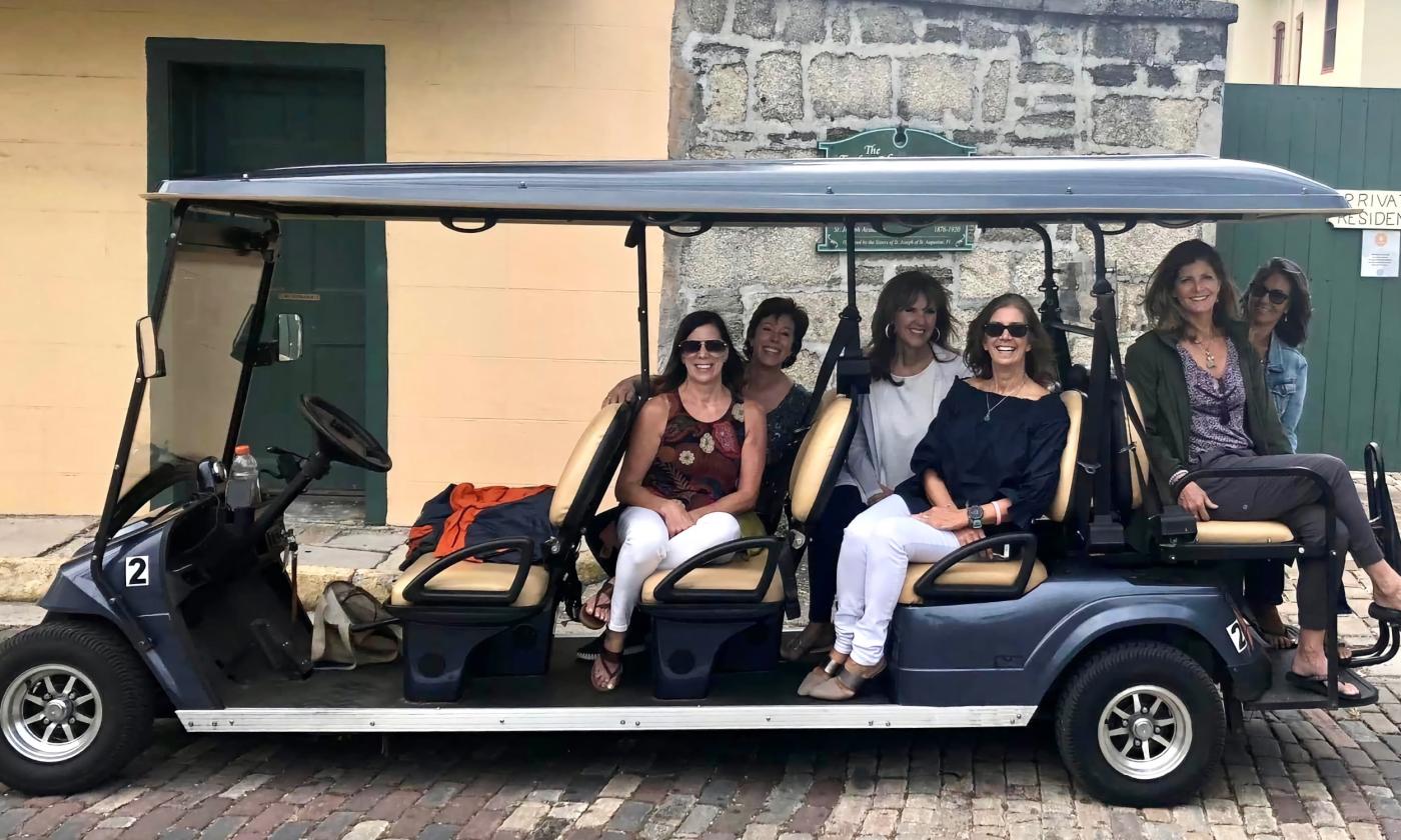 Gold Tours with their green large EV, on a St. Augustine Street with clients aboard