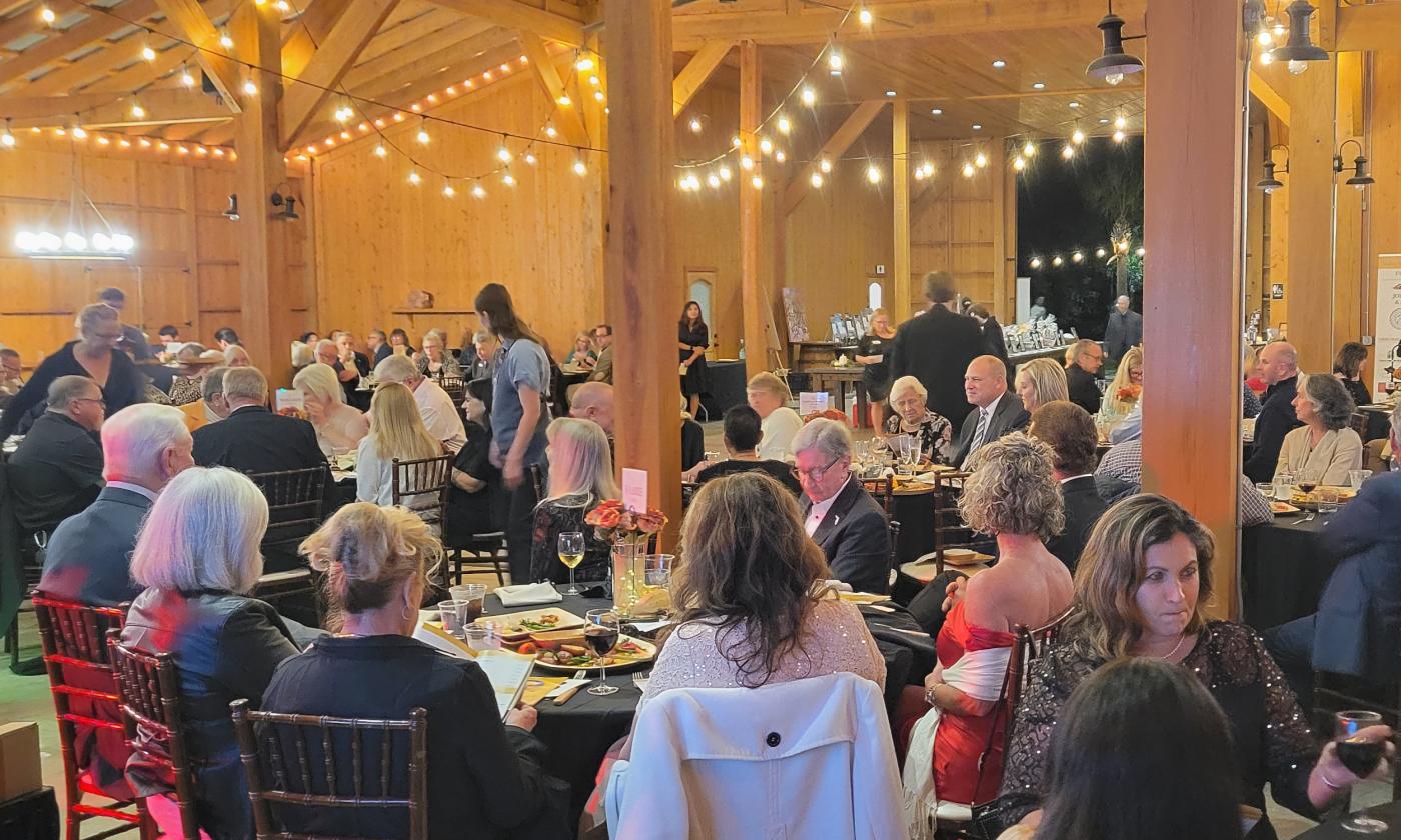 Guests at the Under the Moon Gala sitting at tables for 8 in the decorated Tringali Barn