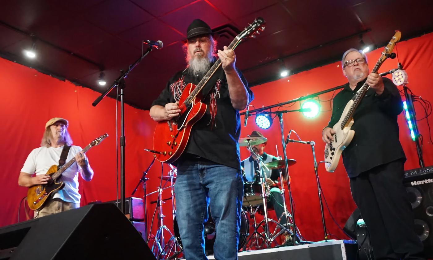 The four members of Mojo Healers performing in a studio against a bright red background