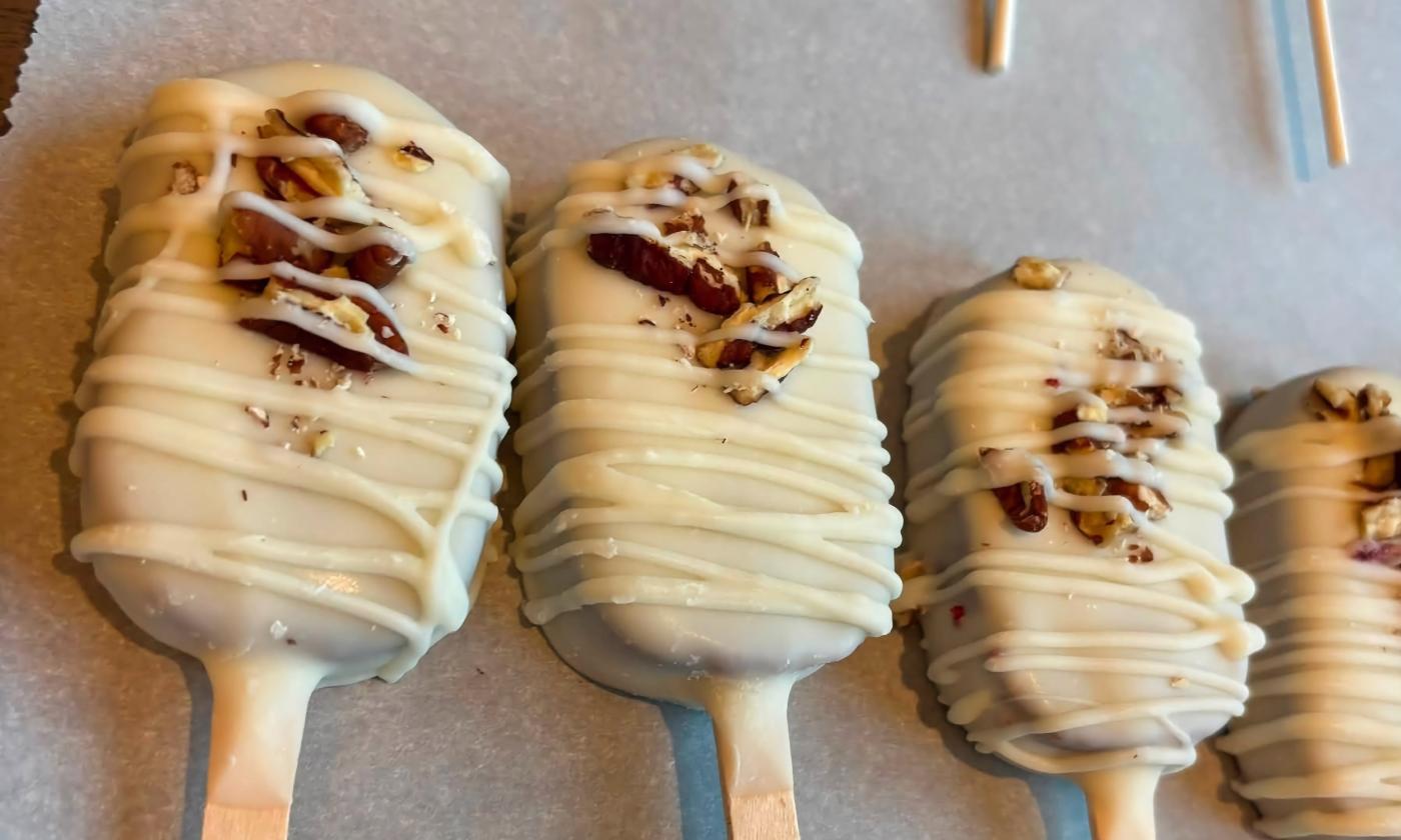 A row of cake pops topped with pecans